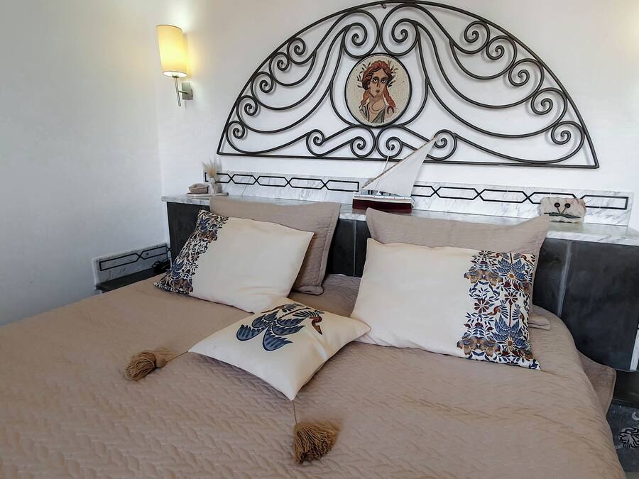 Una cama bien tendida con almohadas estampadas y un cabecero decorativo.