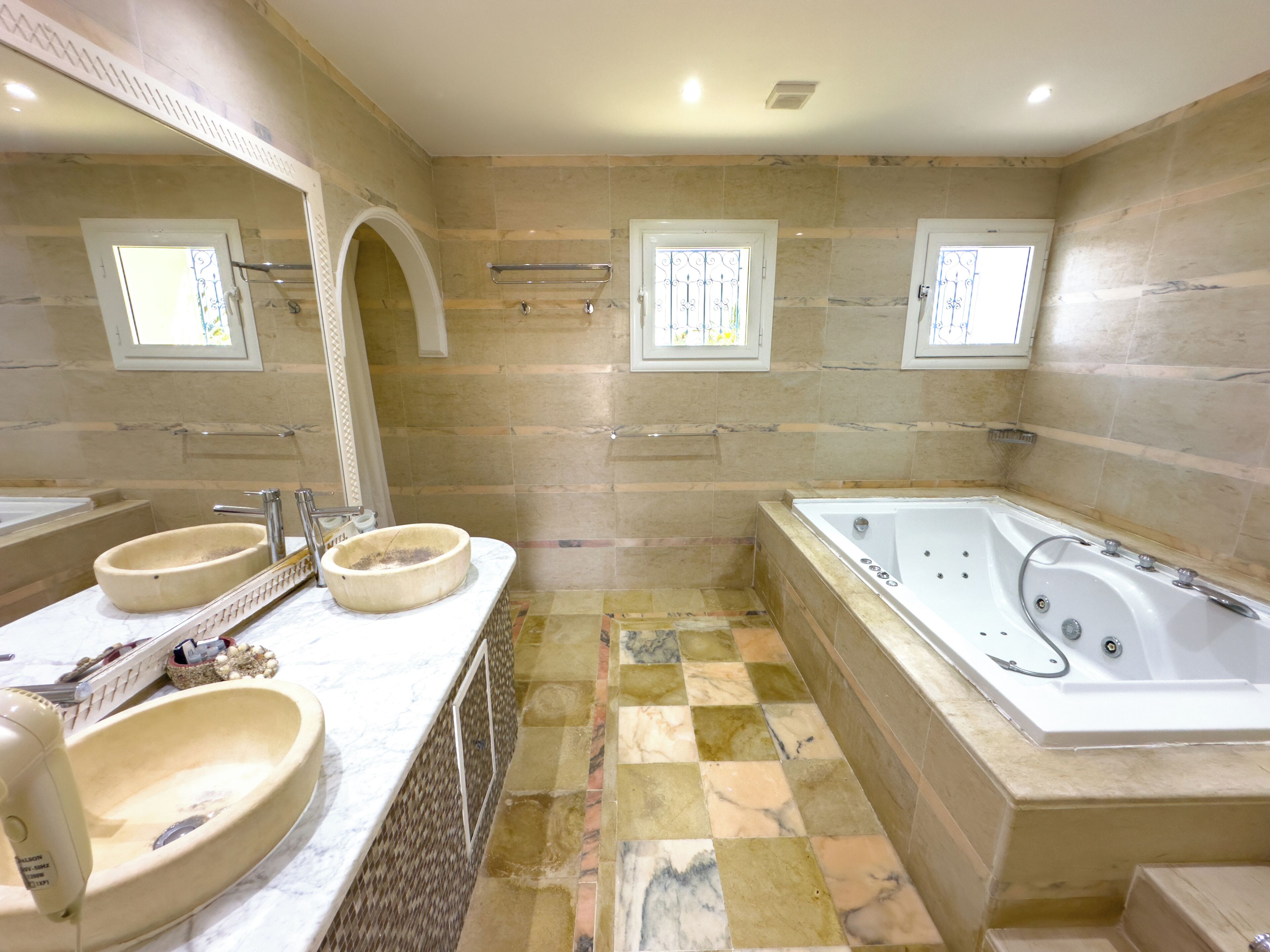 A bathroom with a large bathtub, two sinks, and a shower area.