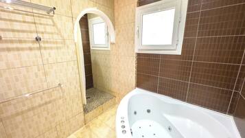 A bathroom with a bathtub, a shower area, and a mirror.