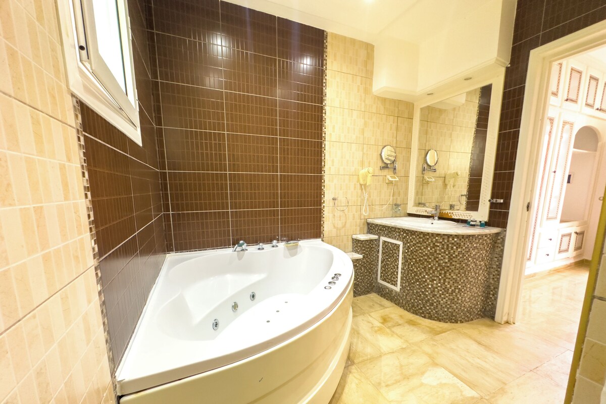 A bathroom with a large bathtub, a sink, and a mirror.