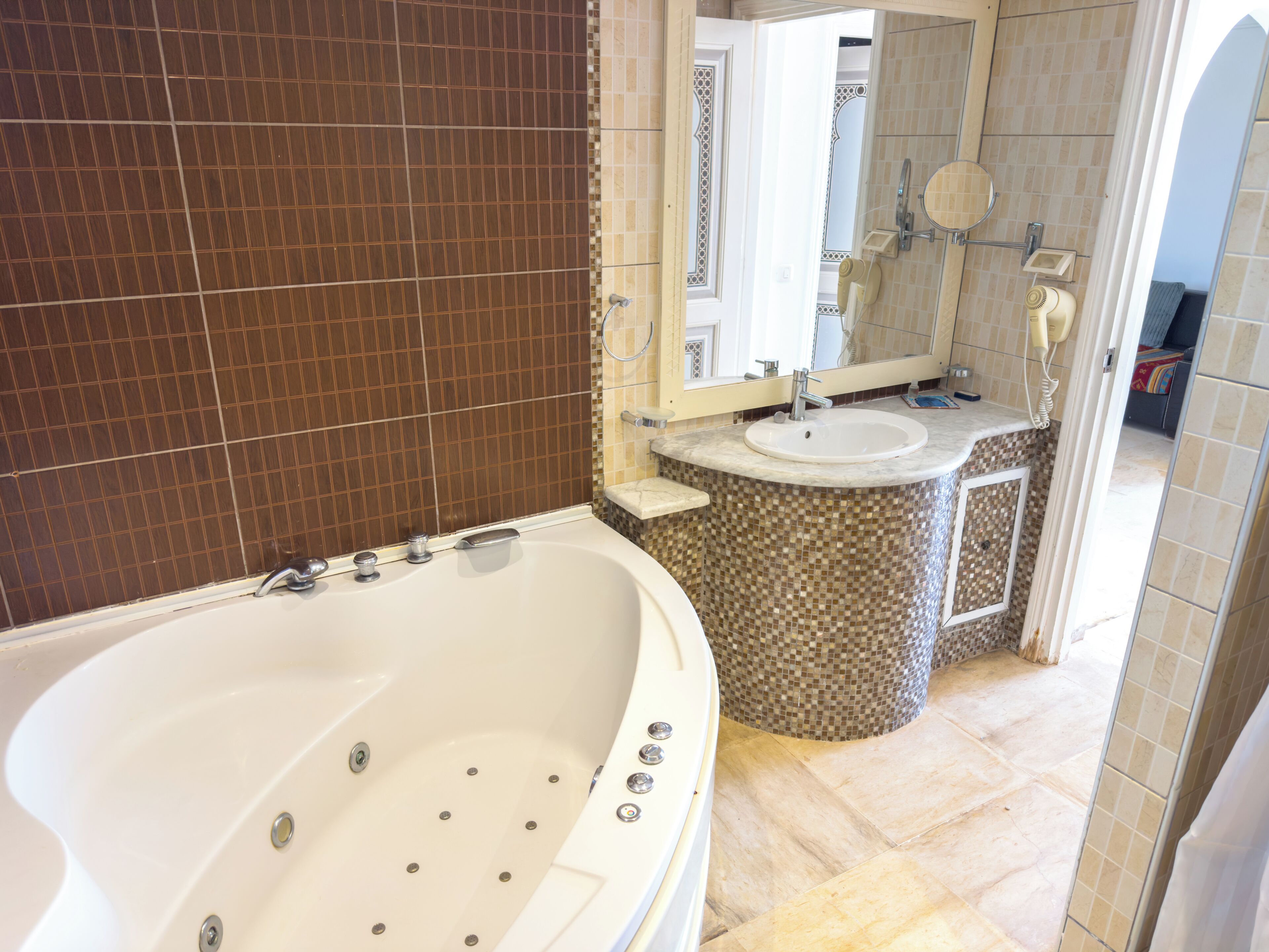 A bathroom with a large bathtub, a sink, and a mirror.