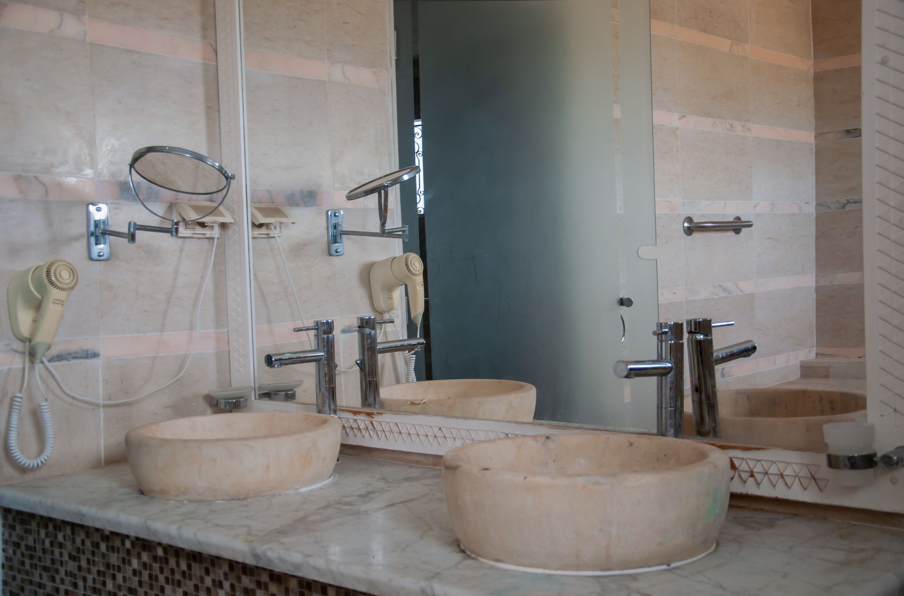 A bathroom with three wooden sinks, a hairdryer, and a telephone.