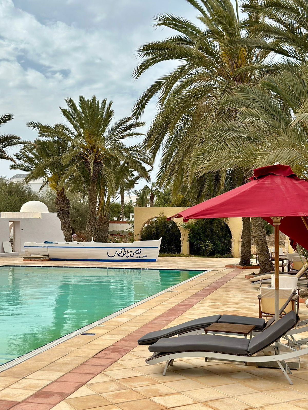 A poolside area with lounge chairs and a boat.