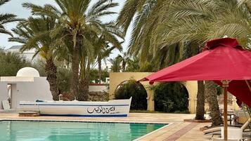 A poolside area with lounge chairs and a boat.