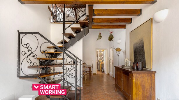 Ein großzügiger Wohnbereich mit moderner Treppe, einem Holzschrank und einem großen Gemälde an der Wand.
