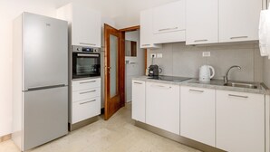 Een moderne keuken met witte kastjes, een inbouwoven en een koffiezetapparaat.