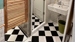 Un baño con piso a cuadros, un lavamanos, un espejo y una puerta de ducha.