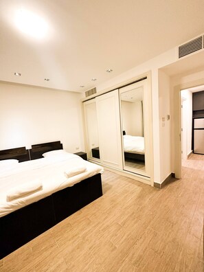 A modern bedroom with a bed, a wardrobe, and a mirror. - Central Apartment For Rent 26 (Amman)