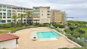 Un hotel con piscina, varios balcones y vista al mar.