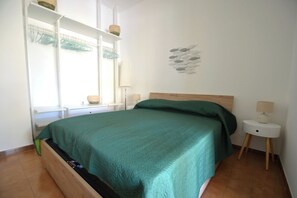 Ett sovrum med en säng, ett nattduksbord, en lampa, en väggdekoration och ett fönster med utsikt.