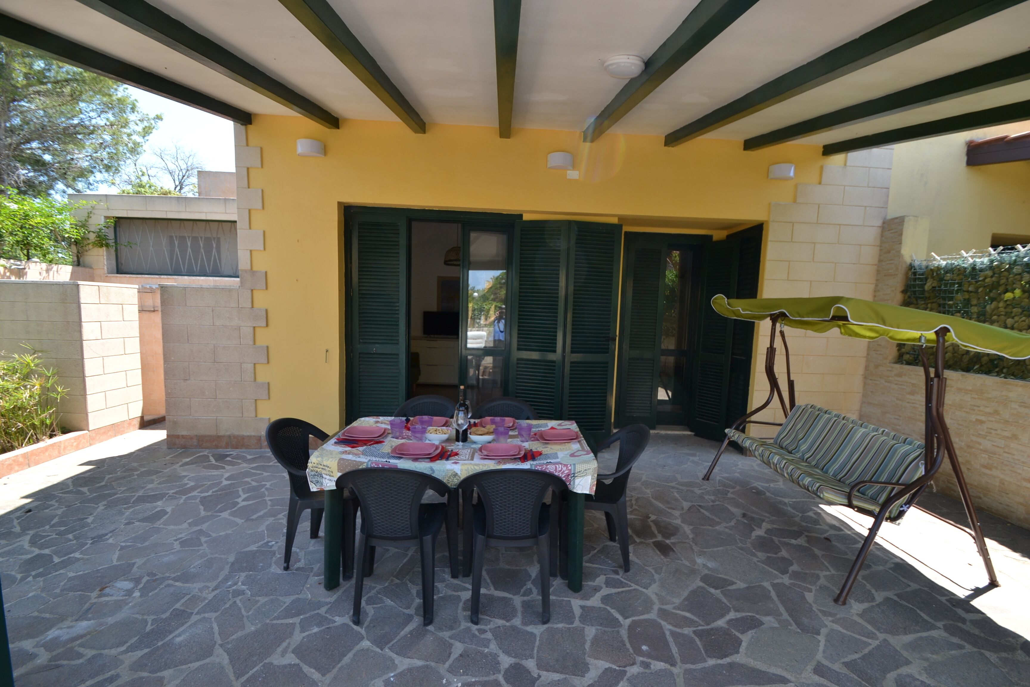 A patio with a table set for dining, outdoor seating, and a covered area.