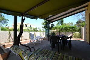 An outdoor patio with a covered seating area, a table with chairs, and a view of the surrounding landscape. - Villetta Gianira With Shaded Garden and air Conditioning Pt58 (Melendugno)