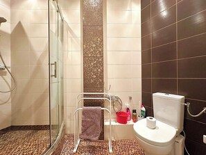 Une salle de bain avec une douche à parois de verre, des toilettes et un lavabo équipé de produits de toilette.