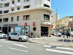 Un bâtiment à la façade incurvée, une enseigne indiquant « CAISSE D’ÉPARGNE » et un panneau « INTERDICTION DE STATIONNER ».