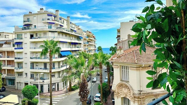 Une zone urbaine côtière avec des immeubles à plusieurs étages, des palmiers et un ciel dégagé.