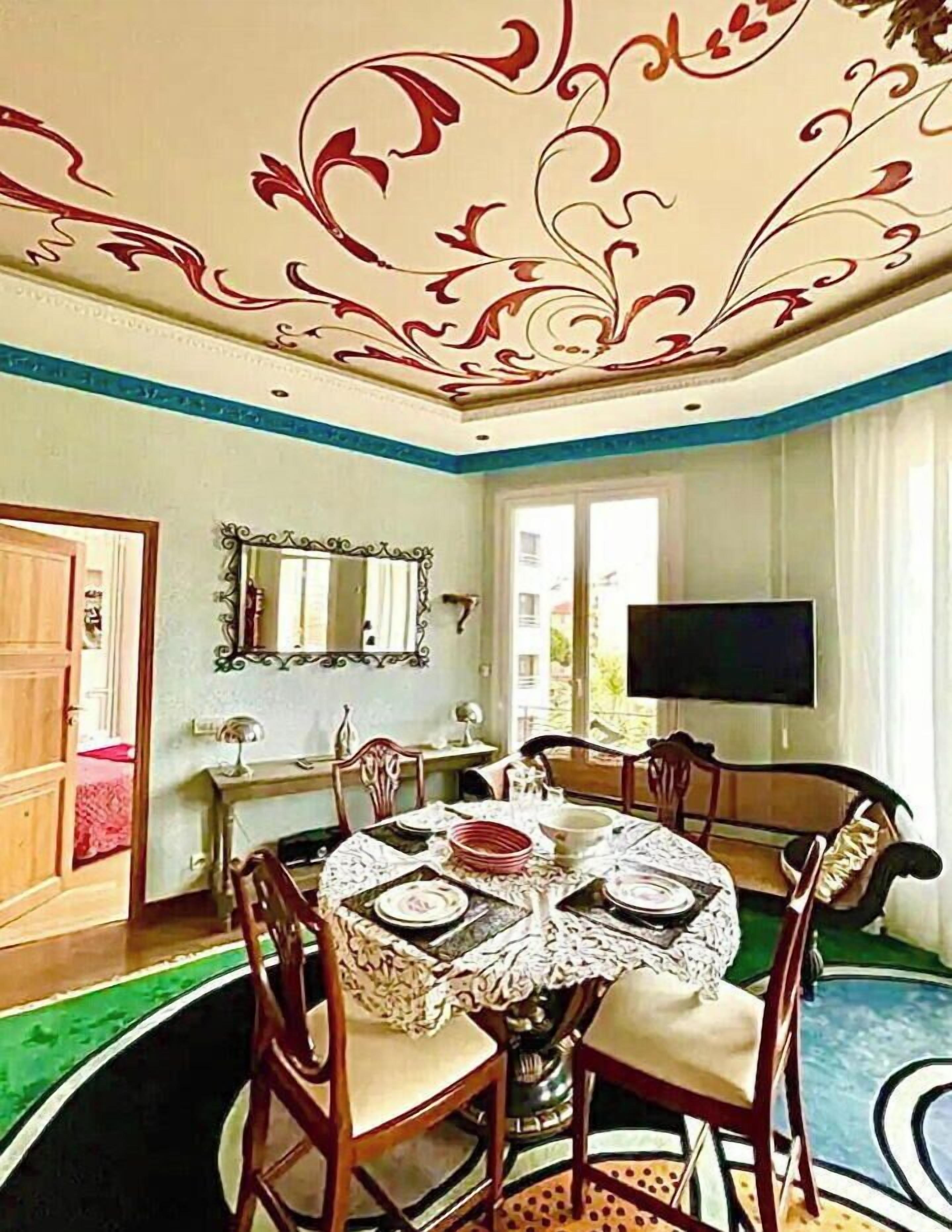 Una sala da pranzo con un tavolo rotondo, sedie, uno specchio e una televisione.