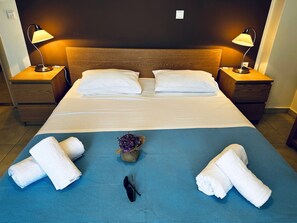 Ett hotellrum med en stor säng, två sängbord, två lampor och ett blått sängöverkast.