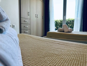 Hotellihuone, jossa on sänky, ikkuna verhoilla, pieni pöytä pyyhkeineen ja vaatekaappi.