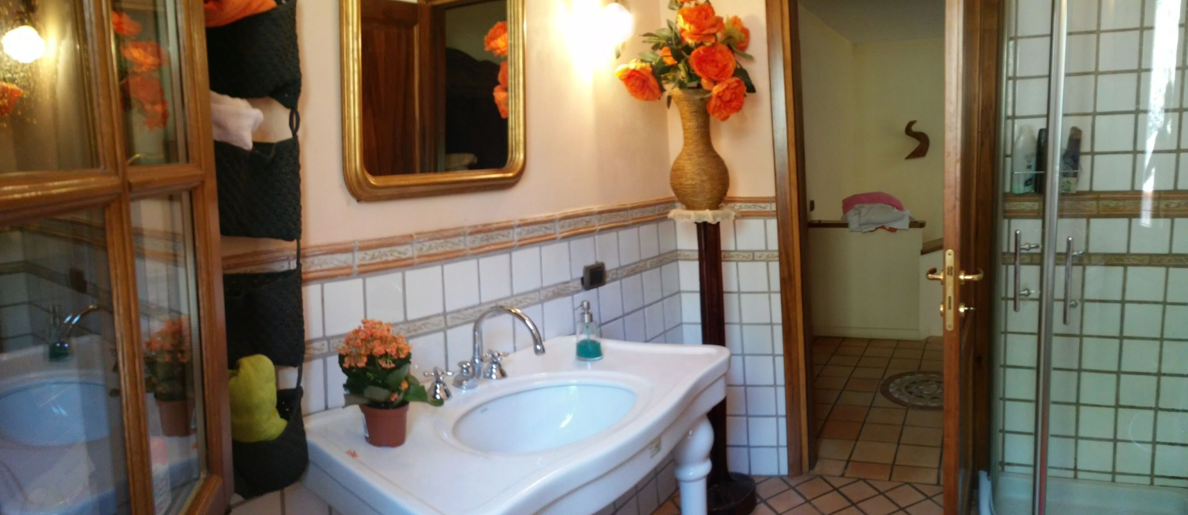 A bathroom with a sink, mirror, and a vase with flowers.