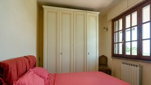Une chambre à coucher avec un lit, une armoire, une chaise et une fenêtre donnant sur un beau paysage.
