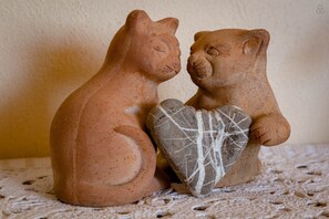 Two terracotta bear figurines sitting on a textured surface.