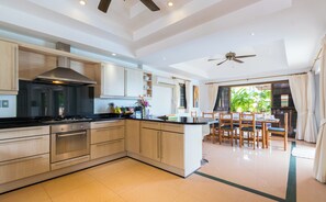 Enjoy meals in the spacious kitchen with a central island, stove, and oven, adjacent to a dining area with a wooden table and chairs.