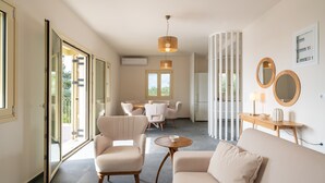 A spacious living area with a sofa, chairs, a dining table, and a kitchen in the background. - The Cerulean Villa - The Concord Of Blue And Green! (Kefalonia)