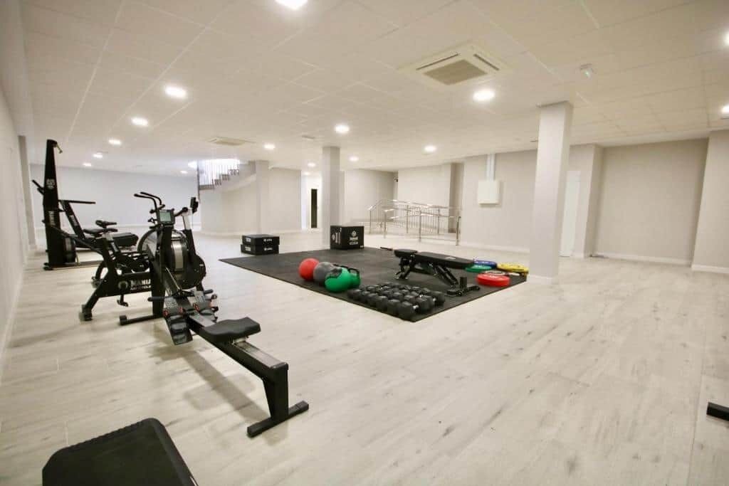 Une salle de sport spacieuse équipée de machines de cardio, de matériel de musculation et de différents types de ballons d’exercice.