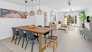 Un salon moderne comprenant un canapé, une table basse et un coin repas avec une table et des chaises en bois.