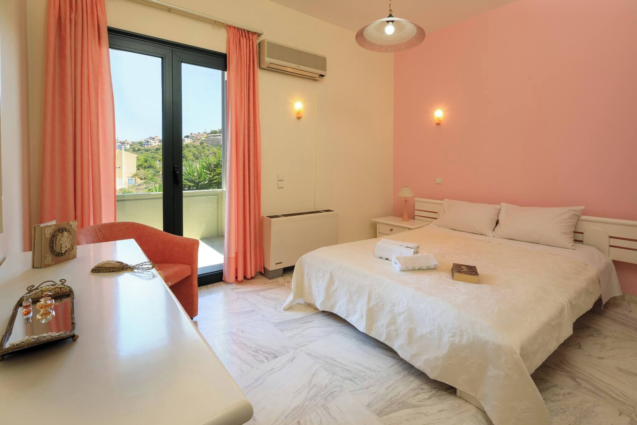 Un dormitorio con cama, escritorio, silla y vistas por la ventana.