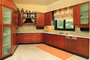 A kitchen with wooden cabinets, a tiled backsplash, a window with a floral curtain, and a stainless steel sink.