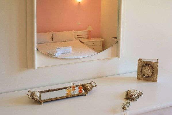 A bedroom with a bed, bedside table, and a mirror reflecting the room.
