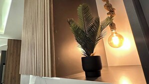 Un interno moderno con una pianta in vaso, un lampadario a sospensione e un pannello a listelli di legno.