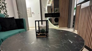 Un'area pranzo moderna con un tavolo in marmo nero, un divano verde e un piccolo centrotavola con una pianta.