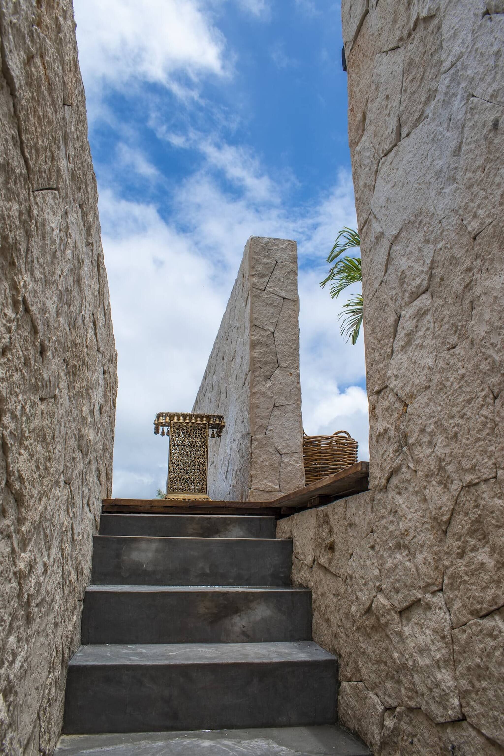 A stone staircase leading to a platform with a decorative column, surrounded by large stone walls.
