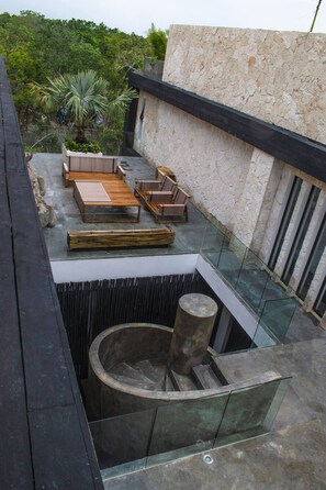 A rooftop terrace with a stone wall, a palm tree, and a seating area with wooden furniture. - Bh 07 - Penthouse Glamorous Zen In The Jungle (Tulum)