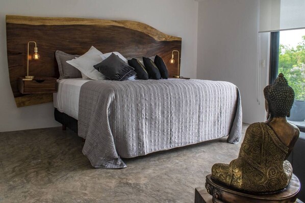 A bedroom with a large bed, a wooden headboard, bedside lamps, and a Buddha statue. - Bh 07 - Penthouse Glamorous Zen In The Jungle (Tulum)