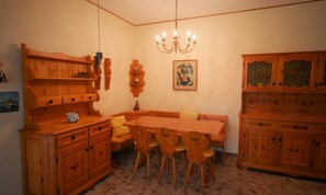 A dining area with wooden furniture, a chandelier, and a painting on the wall.