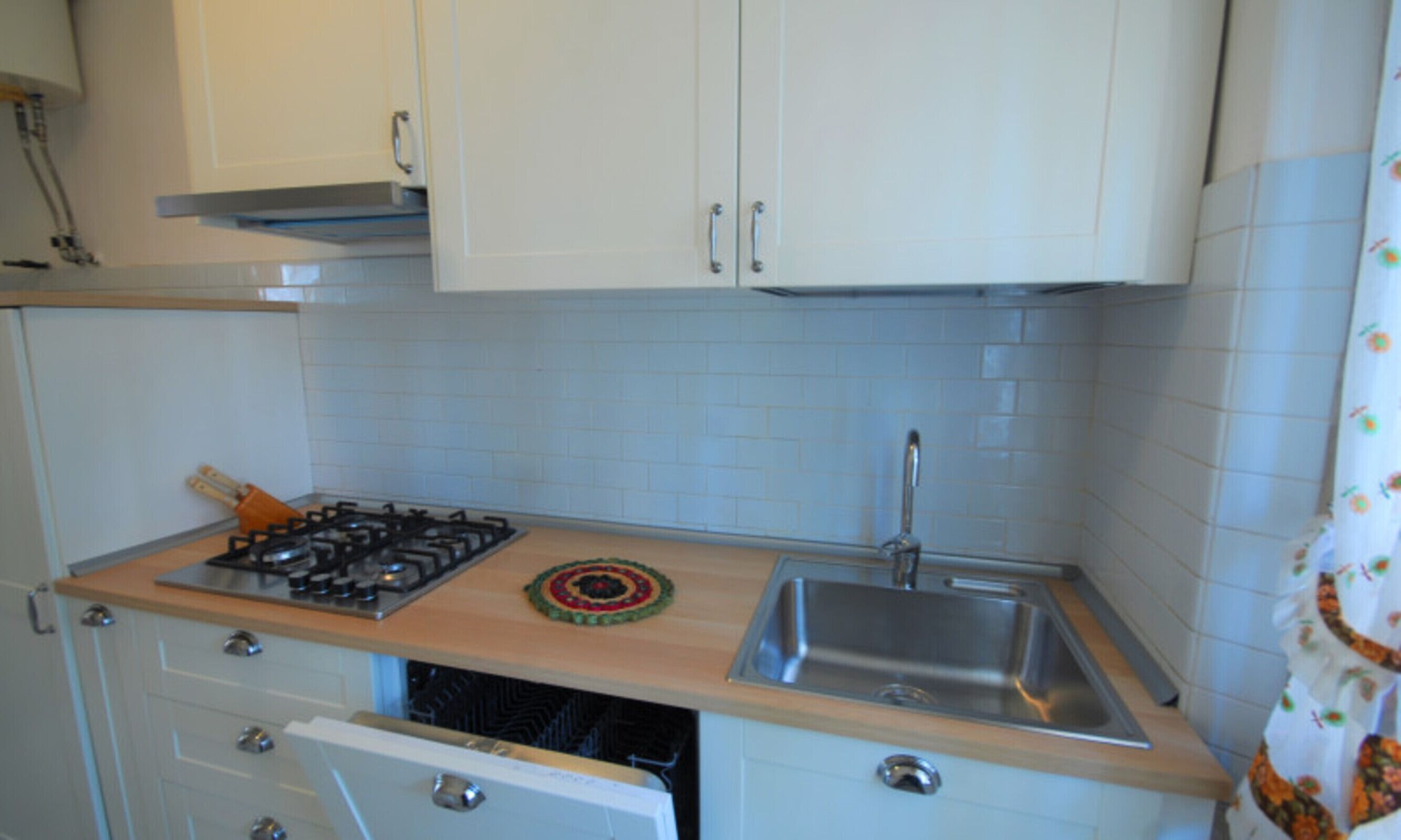 A kitchen with white cabinets, a gas stove, a sink, and a dishwasher.