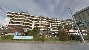 En bygning med flere etager, et parkeringsskilt, et restaurantskilt og en blå himmel.