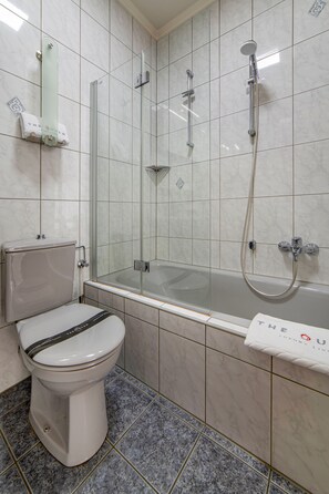 Une salle de bain comprenant des toilettes, une douche à parois de verre et une baignoire.