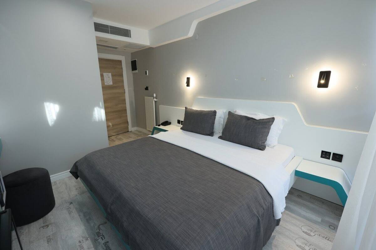 Una camera d'albergo moderna con un letto grande, un comodino e un tavolino.