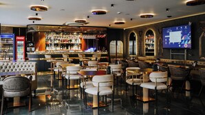 A modern bar area with a bar counter, seating, and a television screen. - Midis Otel (Edirne)