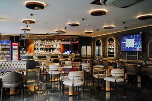 A modern bar area with a bar counter, seating, and a television screen.