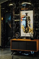 A lobby with a marble wall, a framed poster, and a wooden console with a vintage radio.