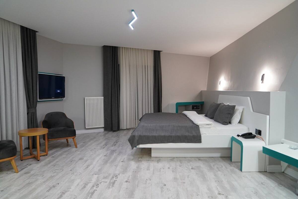 Una camera d'albergo moderna con un letto grande, una televisione, un tavolino e una sedia.