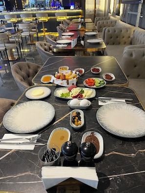 Una mesa de comedor dispuesta con diversos platos, incluyendo un tazón de aceitunas, un plato de verduras en rodajas y un tazón de sopa.
