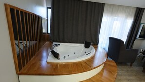 A modern bathroom with a freestanding bathtub, wooden flooring, and a dark curtain. - Midis Otel (Edirne)