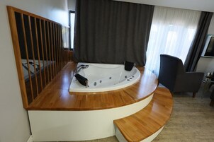 A modern bathroom with a freestanding bathtub, wooden flooring, and a dark curtain.