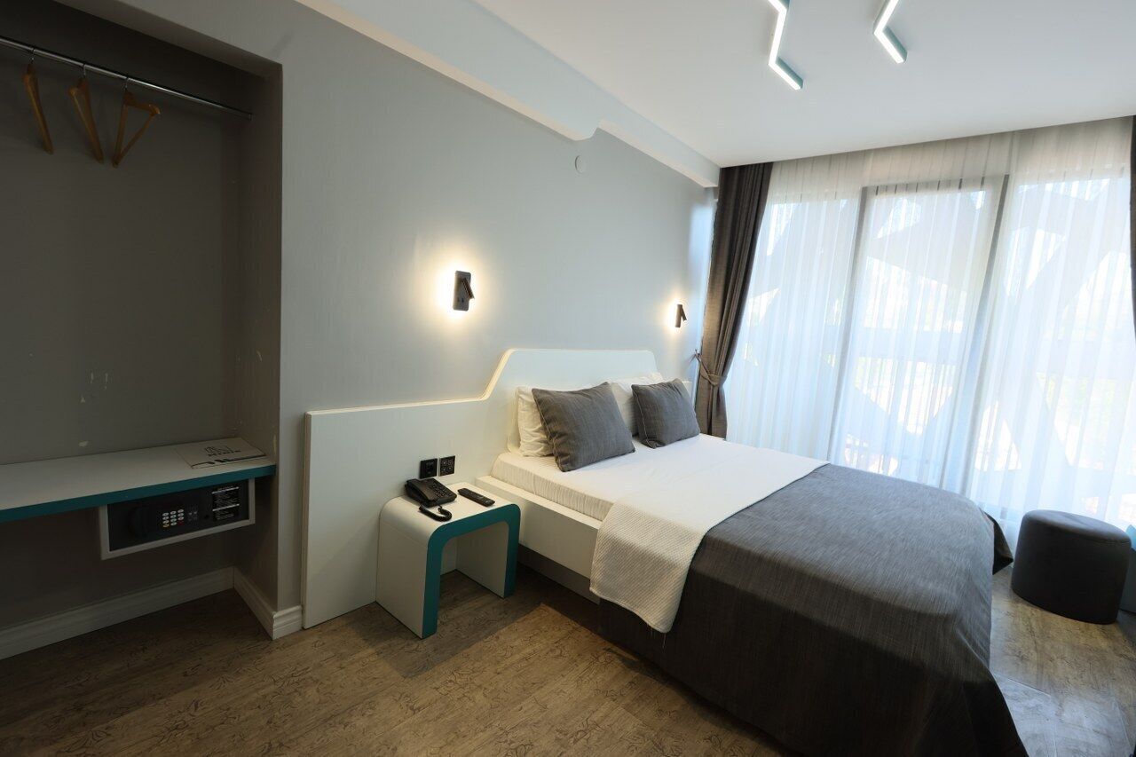 Une chambre d’hôtel moderne équipée d’un lit, d’une table de chevet et d’une armoire intégrée.